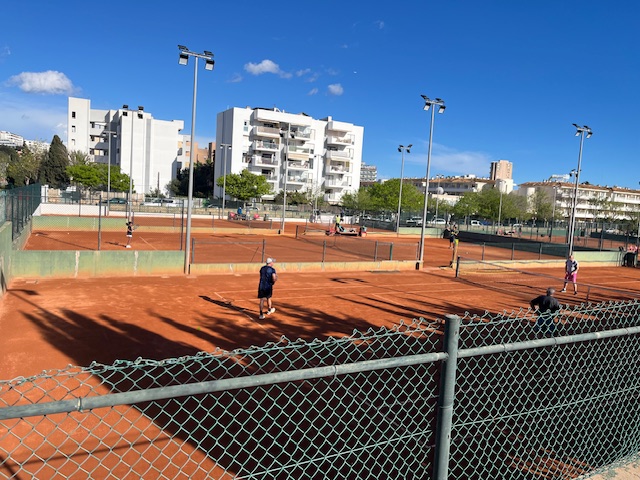 The tennis courts on a sunny day, with hotels in the background.